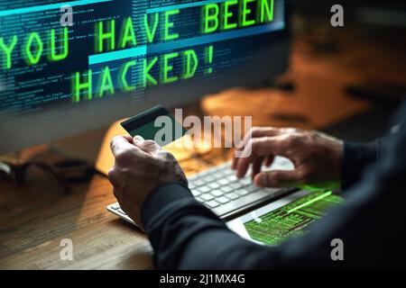 Jemand ist für eine böse Überraschung bereit. Ausgeschnittene Aufnahme eines nicht identifizierbaren Hackers, der im Dunkeln einen Computercode knackt. Stockfoto