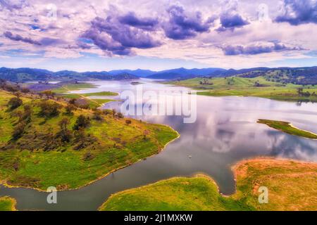 Lake Windamere am Cudgegong River mit kleinem Fischerboot in der grünen hügeligen Region von NSW, Australien - Luftpanorama. Stockfoto