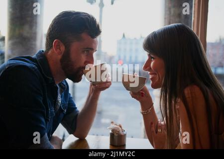 Verbindung über Kaffee. Eine kurze Aufnahme eines anhänglichen jungen Paares, das in einem Café sitzt, während er ein Date hat. Stockfoto