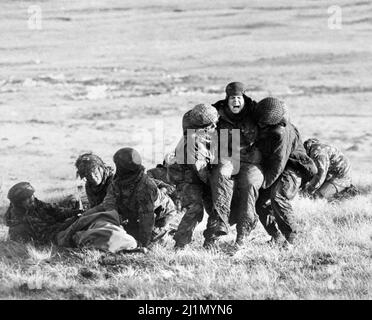 Aktenfoto vom 04/06/82 von britischen Fallschirmjägern, die während der Falklands-Kampagne unter Beschuss auf dem Mount Longdon eine medizinische Notfallbehandlung verwundeten Kameraden durchgeführt haben. Anlässlich des 40.. Jahrestages des Endes des Falklandkrieges wird in den kommenden Tagen eine Reihe von Vorträgen, Gedenkstätten, Ausstellungen und anderen Veranstaltungen gestartet. Ziel ist es, an die Opfer des Jahres 1982 zu erinnern und die Fortschritte zu feiern, die in den letzten 40 Jahren auf den Inseln im Südatlantik erzielt wurden. Ausgabedatum: Sonntag, 27. März 2022. Stockfoto