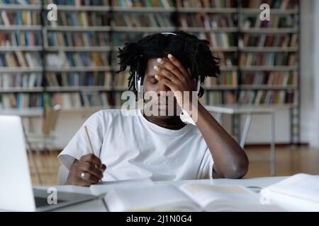 Afrikanischer Student fühlt sich müde aufgrund langer Vorbereitungen für College-Prüfung Stockfoto