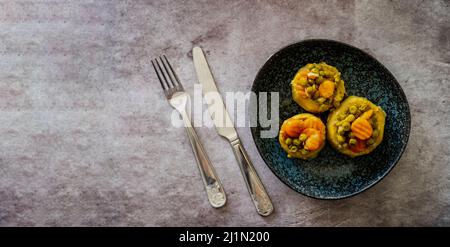 Gekochte stachelige Artischocke mit Olivenöl und Karotten und Erbsen, Draufsicht, selektive Focos Stockfoto
