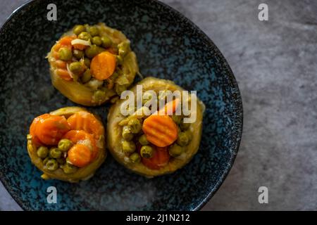 Gekochte stachelige Artischocke mit Olivenöl und Karotten und Erbsen, Draufsicht, selektive Focos Stockfoto