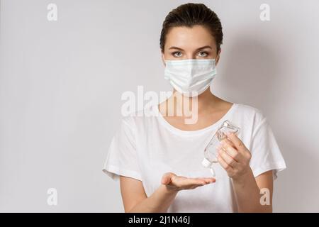 Die Frau schützt sich vor dem Virus. Verwenden von Händedesinfektionsmittel und Gesichtsmaske. Stockfoto