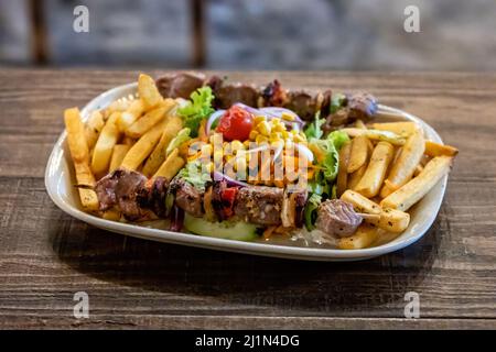 Teller mit portugiesischen Nationalgerichten Fleischspieße und Gemüse auf Restauranttisch, selektiver Fokus Stockfoto