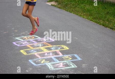 Kleines Mädchen spielt hopscotch. Selektiver Fokus Stockfoto