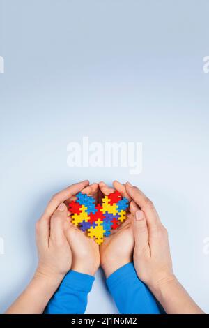 Konzept des Welt-Autismus-Tages. Erwachsene und Kinder Hände halten Puzzle Herz auf hellblauem Hintergrund. Draufsicht Stockfoto