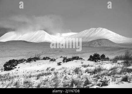Schwarz-Weiß-Alpen Glow trifft Berggipfel in den schottischen Highlands während eines atemberaubenden Sonnenaufgangs in der Winterlandschaft Stockfoto