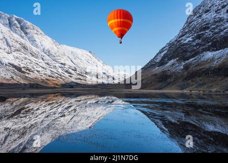Digitales Composite-Bild von Heißluftballons, die über die wunderschöne Winterlandschaft des Loch Achtriochan in den schottischen Highlands fliegen Stockfoto