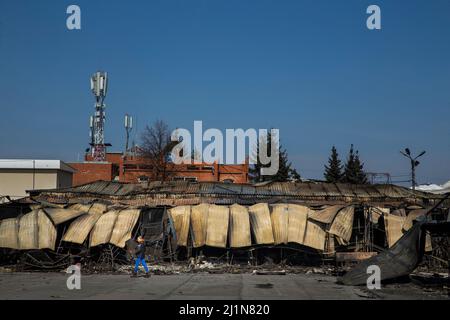 Charkiw, Ukraine. 26. März 2022. Eine Frau kommt am 26. März 2022 an den Resten eines Gebäudes vorbei, das durch russische Schüsse auf dem Markt Barabaschowo in Charkiw, Ukraine, beschädigt wurde. Die Angriffe Russlands waren heute weniger häufig als in früheren Tagen, da ukrainische Truppen russische Einheiten zurückdrängen. (Bild: © Daniel Carde/ZUMA Press Wire) Stockfoto