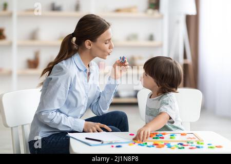 Junge Frau Logopädin, die kleinen Jungen mit Aussprache unterrichtet, deffects, Ton U während des Trainings zu sagen Stockfoto