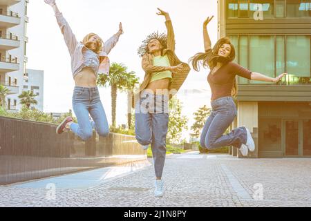 Glücklich schöne drei Frau im Freien springen, junge unbeschwerte weibliche Freunde feiern Sieg ragende Arme, Glück und erfolgreiches Konzept Stockfoto