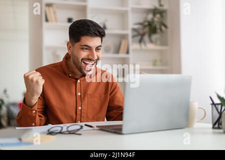 Begeisterter Mann mit Laptop feiert Erfolg Schütteln Fäuste schreiend ja Stockfoto