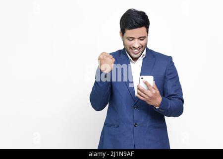 Aufgeregt asiatische indische männlich mit Smartphone auf isoliertem Hintergrund. Stockfoto