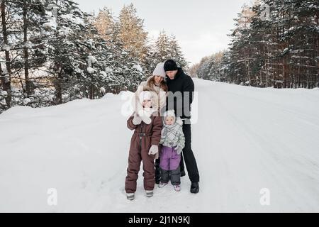 Vater, Mutter und zwei Töchter wandern durch den verschneiten Wald Stockfoto