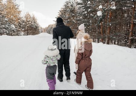 Vater, Mutter und zwei Töchter wandern durch den verschneiten Wald Stockfoto