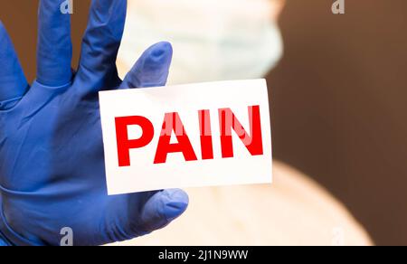 Schmerzkarte in der Hand des Arztes. Konzept zur Schmerzlinderung im Gesundheitswesen. Stockfoto