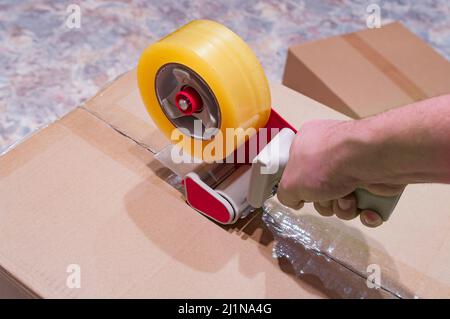 Verpackung von Paketen mit Scotch Tape Dispenser close-up Stockfoto