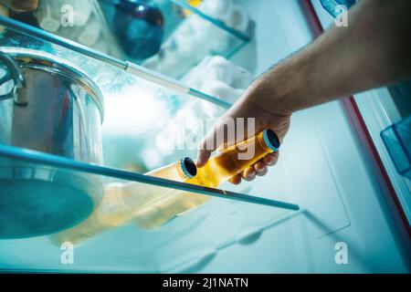 Nahaufnahme die Hand eines Mannes nimmt eine Flasche Bier aus dem Kühlschrank Stockfoto