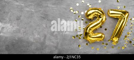 Gelbe Folienballon-Nummer, Nummer siebenundzwanzig auf betonem Hintergrund. Geburtstagskarte mit Aufschrift 27. Jubiläumskonzept. Zum Jubiläum Stockfoto