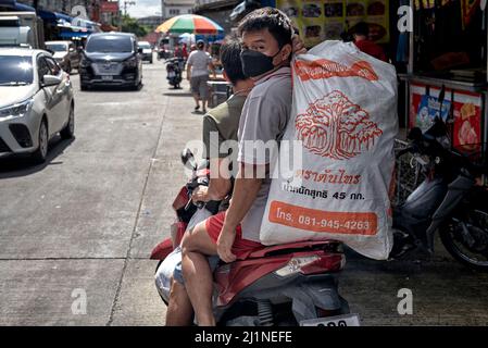 Motorradlieferung mit Beifahrer, der eine große Sackladung auf der Rückseite eines Motorrads trägt. Thailand Südostasien Stockfoto