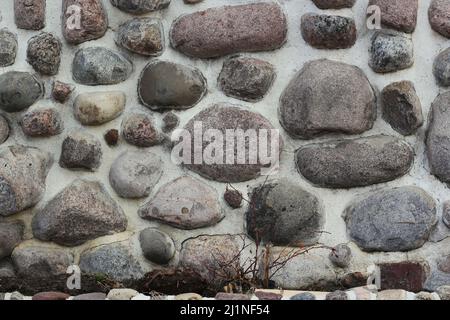 Eine natürliche Granitsteinwand aus runden Felsbrocken. Stockfoto