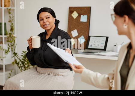 Porträt zweier erfolgreicher Geschäftsfrauen, die im Minimalbüro über Dokumente diskutieren Stockfoto
