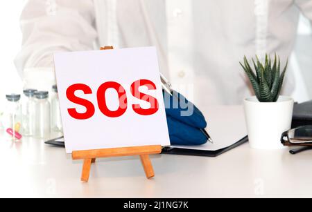 Hinweis Mit SOS Inschrift. Haftnotiz mit SOS-Inschrift auf einem Kork Pinnwand angeheftet Stockfoto