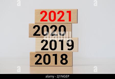 Geschäftsmann baut Holzblöcke 2018, 2019, 2020, 2021. Das Konzept des Beginns des neuen Jahres. Neue Ziele. Nächstes Jahrzehnt. Trends und Veränderungen in t Stockfoto