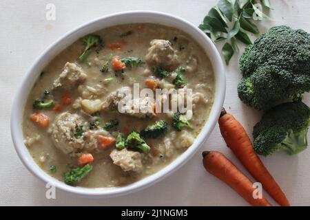 Geschmortes Huhn mit Gemüse. Kerala-Zubereitung mit Karotten, Brokkoli, Kartoffeln, Hühnchen, Kokosmilch und Gewürzen. Aufgenommen auf weißem Hintergrund Stockfoto