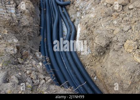 Schwarze Drainagerohre aus Wellkunststoff, die in einem Graben auf einer Baustelle verlegt werden Stockfoto