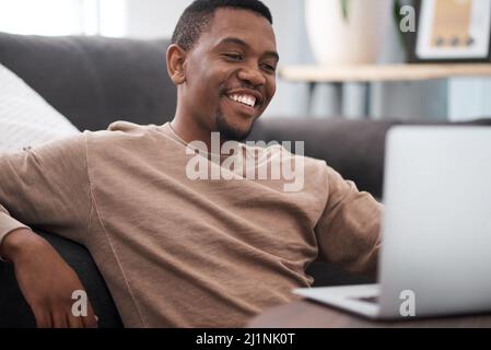 Soziale Distanzierung muss nicht gleich Isolation sein. Aufnahme eines jungen Mannes, der zu Hause einen Laptop benutzt. Stockfoto