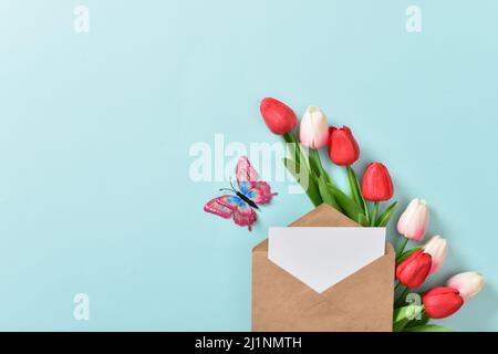 Ein festliches Banner mit Tulpen und einem Umschlag auf hellblauem Hintergrund. Muttertag, Frauentag, Alles Gute zum Geburtstag. Speicherplatz kopieren. Flach liegend, Draufsicht Stockfoto