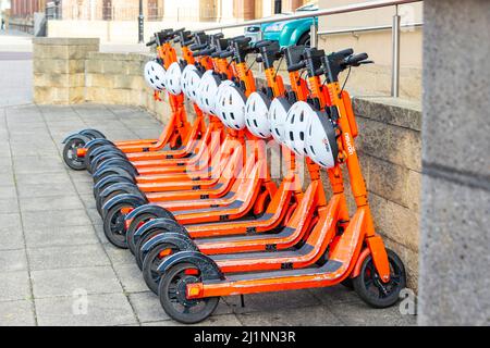 Orange Neurone Mobility E-Scooter zu mieten, die in Newcastle auf Tyne, Großbritannien, hintereinander geparkt sind Stockfoto