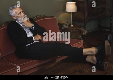 Stilvoller und schöner bärtiger älterer Mann, der sich entspannt Stockfoto
