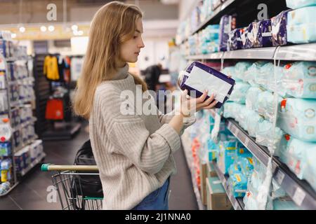 Junge Frau Mutter wählt Windeln im Supermarkt im Einkaufszentrum. Hygieneprodukte für Kinder Stockfoto