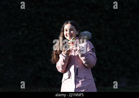 Genf, Schweiz - 03 07 2022 glückliches junges Mädchen mit goldenem osterhase auf Händen. Mädchen feiert Ostern Geschenk im Freien im Park oder Wald.Kleinkind Stockfoto