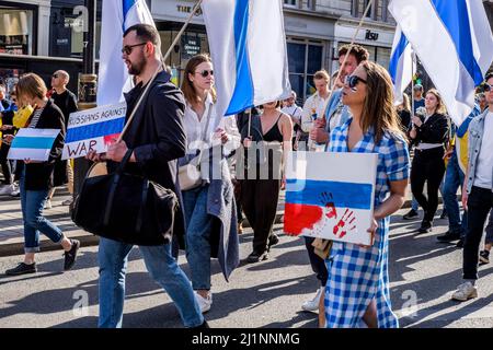 London, 26.. März 2022. Tausende von Menschen treten mit der Ukraine zusammen, marschieren und mahnten im Zentrum von London, um gegen die russische Invasion zu protestieren. Mitglieder der Bewegung gegen den Krieg schließen sich dem marsch an. Die Bewegung hat eine weiße und blaue Flagge als Symbol ihres Protests angenommen, die den roten Streifen der russischen Flagge ersetzt, um die Verbindung mit Blut und Gewalt sowie militärischer Macht und Autoritarismus zu beseitigen. Sie verweist auch auf die historische Flagge von Veliky Nowgorod, wo die Regierung der Republik Nowgorod den Ruf hatte, demokratische Regierungsführung zu entwickeln. Stockfoto