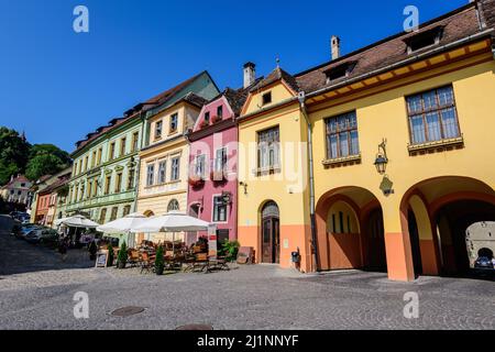 Sighisoara, Rumänien, 13. Juli 2021: Alte bunt bemalte Häuser und Restaurants im historischen Zentrum der Zitadelle von Sighisoara, in Siebenbürgen (TR Stockfoto