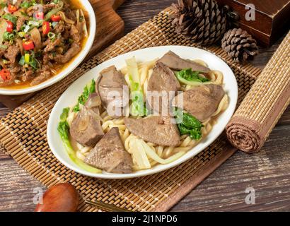 Gebratene Nudeln mit Schweineleber in einem Gericht isoliert auf Matte Seitenansicht auf dunklen Holztisch taiwan Essen Stockfoto