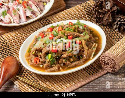 Gebratenes Rindfleisch mit rotem Chili in einem Gericht isoliert auf matter Seitenansicht auf dunklem Holztisch taiwan Essen Stockfoto