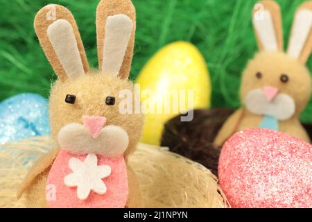 Zwei osterhasen in niedlichen Nestern, umgeben von bunten ostereiern. Stockfoto