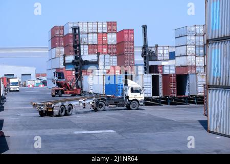 LKW und Containerstapler im Containerlager im Import- und Exportbereich des Hafens Stockfoto