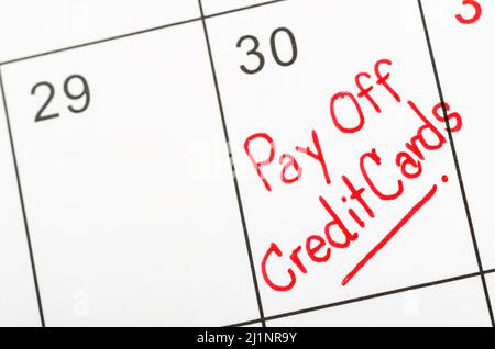 Die Worte Pay off Kreditkarten geschrieben auf einem Kalender. Stockfoto
