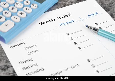 Ein Ausdruck aus einem monatlichen Budget für Ihren Text mit Stift und Rechner auf Holzhintergrund. Stockfoto