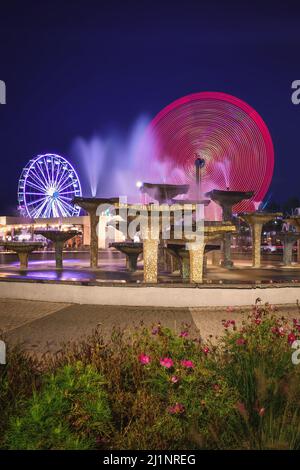 Gdynia, Polen - 22. August 2021: Brunnen und beleuchtete Riesenrad bei Nacht in Gydnia, Polen. Stockfoto