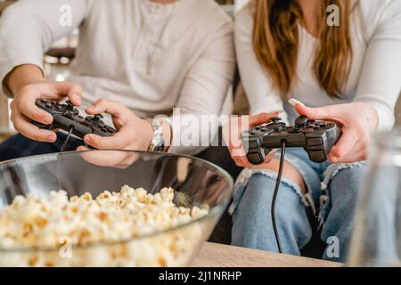 Nahaufnahme der Hände unbekannter Männer und Frauen, die Videospielkonsolen-Controller halten und Videospiele spielen Stockfoto