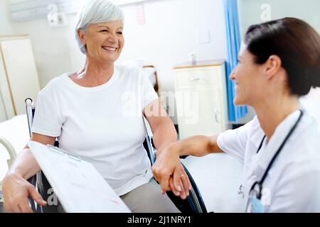 Mit einer helfenden Hand durchkommen. Aufnahme einer schönen jungen Ärztin, die ihrer älteren Patientin gute Nachrichten gab. Stockfoto