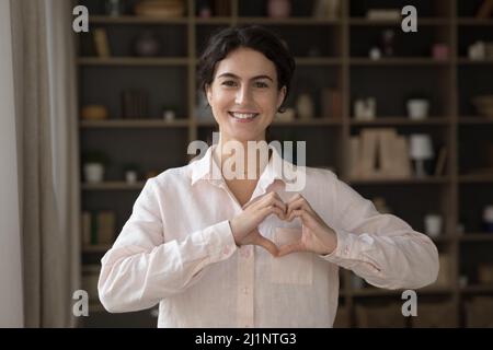 Glücklich schöne lateinische Mädchen zeigt verbundenen Händen an der Brust Stockfoto