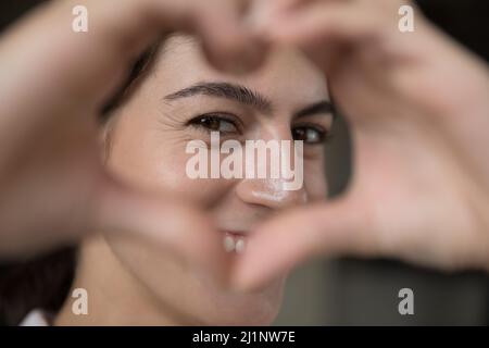 Glücklich schönes Mädchen Blick auf die Kamera durch Herz-Rahmen Stockfoto